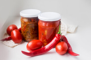 canned red peppers with tomatos in a glass jar on a white background