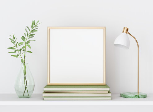 Interior poster mockup with square golden metal frame on white wall decorated with plant in vase, lamp  and books. A4, A3 size format. 3D rendering, illustration.