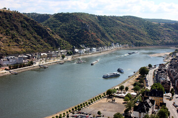 Fototapeta na wymiar Barge with a covered deck sailing on the river Rhine in western Germany, visible buildings on the river bank, aerial view.
