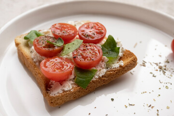 toasts with feta cheese and cherry tomatoes on a white dish, close-up, healthy snack