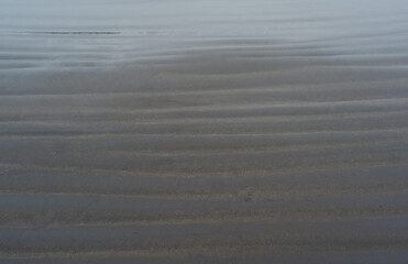 black volcanic sand beach with wave patterns