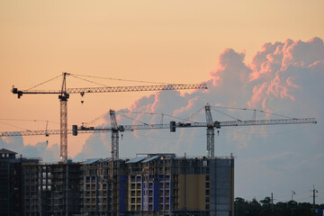 Tower lifting cranes at high residential apartment buildings construction site. Real estate development