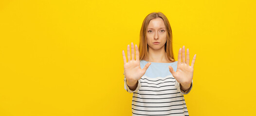 Stop. Young serious woman showing stop sign with palms, stretch out arms, permission denied,...