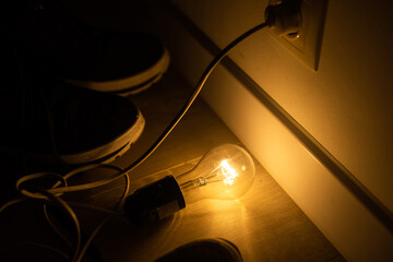 Single lightbulb hanging from a wire in a dark room with a warm glow.