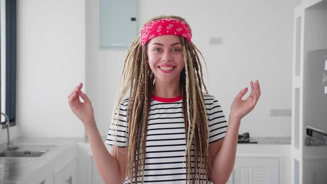 Woman with dreadlocks and red bandana throws paper and rejoices in the win. Modern interior background. Slow motion