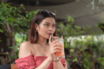 A lovely lady takes a sip of her iced juice as she spends her leisure time at an al fresco...