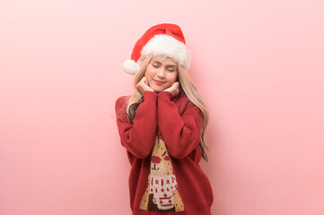 Portrait of happy Caucasian young woman in santa claus hat over pink background