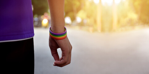 Rainbow wristband wearing in hand of young asian gay to show and represent gender diversity, to respect human rights in alternative sex, to stop punishing homosexuals in some religions.