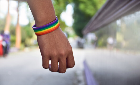 Rainbow wristband wearing in hand of young asian gay to show and represent gender diversity, to respect human rights in alternative sex, to stop punishing homosexuals in some religions.