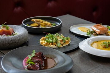 Closeup of tasty multiple cooked dishes in different ceramic plates on the table