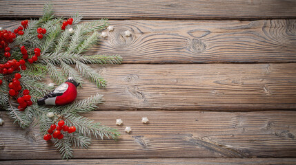 christmas background with red berries, glass bullfinch and fir branches on dark wooden table