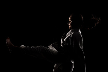 Fototapeta na wymiar Young girl exercising karate. Child in kimono against black background.