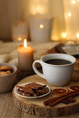 Fototapeta na wymiar Plate of chocolate chip cookies, stack of vintage books, reading glasses, cup of tea or coffee, lit candle and fairy lights. Hygge at home. Selective focus.