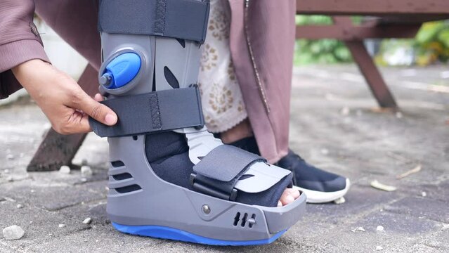 women broken feet with a grey plastic boot ankle brace injury protecting boot