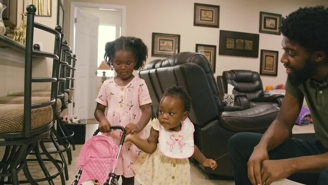 Young Black sisters and Black infant baby girl playing in living room at home