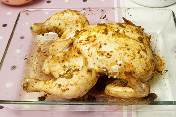 Chicken carcass prepared for baking lies on a glass tray. Home cooking concept.