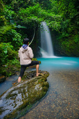 Young man standing on the front of waterfalls with blue water. Traveler on the waterfalls. 