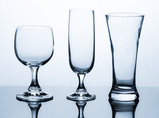 empty glasses of different shapes photographed in front of a white background