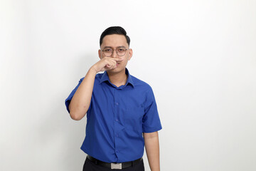 Young asian man standing while showing bad smell gesture. Isolated on white background