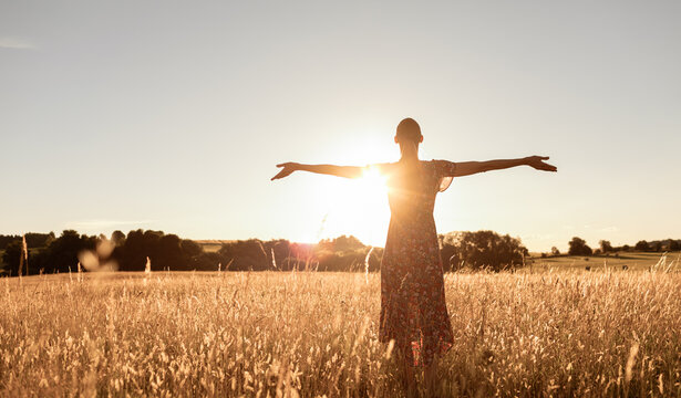 Young woman facing the sun light finding happiness, peace and hope in nature 