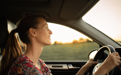 Fototapeta na wymiar Happy young attractive female driving her car early morning 