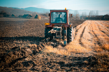 Fototapeta premium Red tractor plowing the grain field