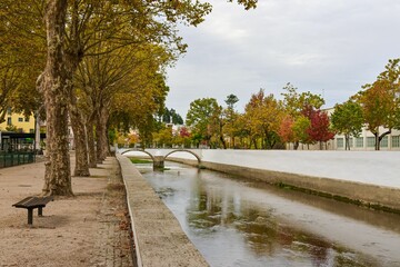 Beautiful shot of the flowing green river Lis with autumn trees on the shore in Leiria, Portugal © João Macedo/Wirestock Creators