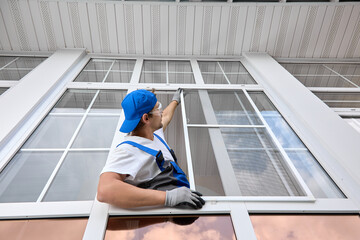 Master for the maintenance of plastic windows installs a protective net against insects for the...