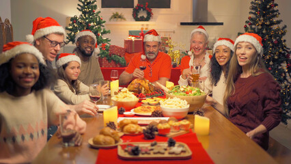 A group of multi ethnic. Portrait of Caucasian and African American black family, woman have a celebration dinner in party on Merry Christmas Eve Xmas on holiday at home.People lifestyle. thanksgiving