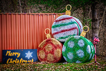 Country - Rural Scene - Big Round Bales Of Hay Painted Like Christmas Ornaments With Merry Christmas Sign In Front Of Repurposed Rail Car And Woods - Room For Copy Wall Mural