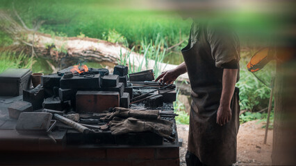 Blacksmith in authentic vintage clothes heats up metal for forging. Added motion blur effect for cinematic look.