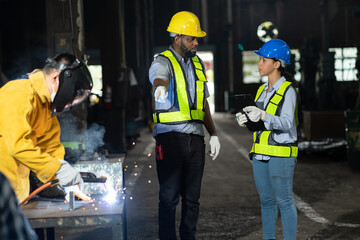 Group of male and female engineer worker discussing of steel welding project at the industry factory area. Team of technician wear safety uniform working and discussion in the factory