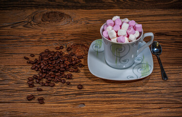 Cup filled with marshmallows with coffee beans on a wooden background.