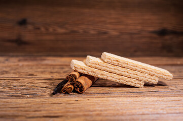 Wafers, cinnamon sticks and vanilla stick on a wooden background