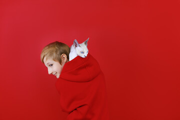 boy dressed in a red tracksuit with a cat on his shoulders on a red background