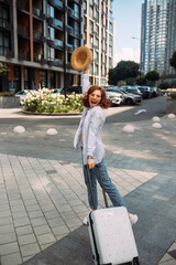 Stylish woman with suitcase looking at camera