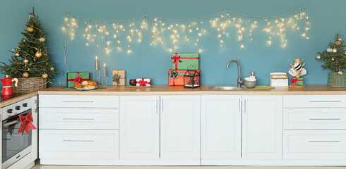Modern interior of kitchen with Christmas trees, gifts and glowing garland