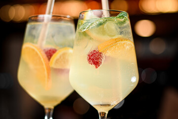 Close-up of alcohol drink of raspberry mojito in glasses with straw and ice cubes.