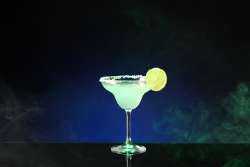 Glass of tasty margarita cocktail on dark color background