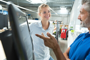 colleagues talking next to system computer in a factory