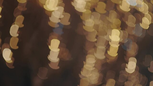 Textured blur shot of outside lights in shape of cylinder hat. City lights bokeh dyring snow on holidays concept.