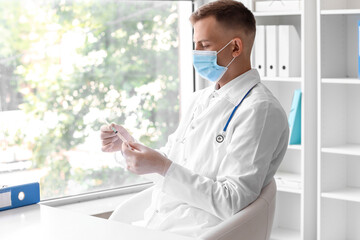 Male doctor in medical mask with syringe at hospital