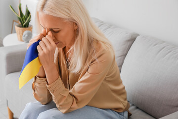 Mature woman with flag of Ukraine praying at home