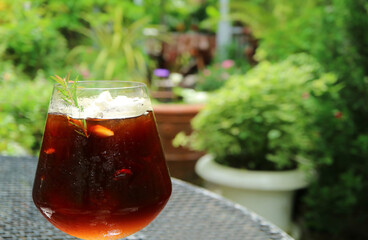A Glass of Iced Coffee with Blurry Green Foliage in the Backdrop