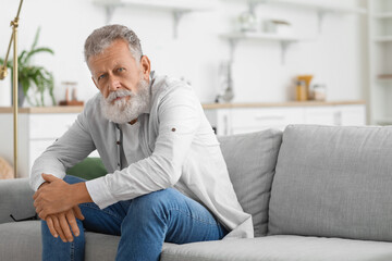 Senior bearded man sitting on sofa in kitchen