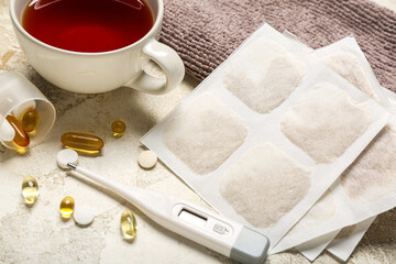 Mustard plasters with pills, thermometer, cup of tea and towel on grunge background, closeup