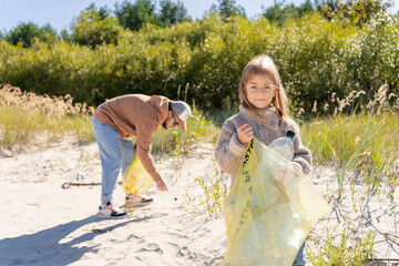 Earth day. Cleanup garbage on the ocean coast. A volunteers Father and daughter with polyethielene...
