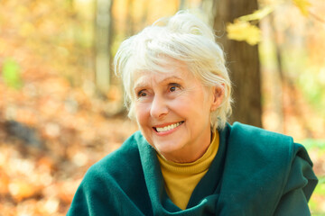 Happy elderly senior woman in an autumn park.