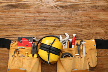 Bag with builder's tools and hearing protectors on wooden background