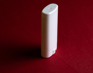 White plastic packaging used to store dermo cosmetics and for application mainly to the skin of the face. On a dark red background and highlighting the packaging's drive mechanism.